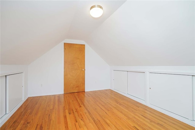 additional living space with light wood-type flooring and lofted ceiling