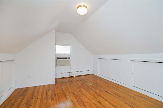 additional living space featuring lofted ceiling, cooling unit, wood finished floors, baseboards, and baseboard heating