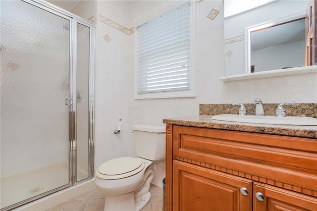 bathroom with vanity, toilet, an enclosed shower, and tile walls