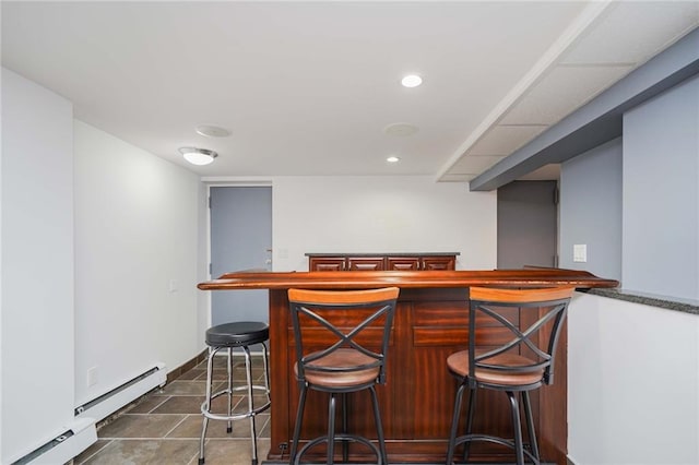 bar featuring a baseboard radiator, recessed lighting, dark tile patterned floors, baseboards, and a bar