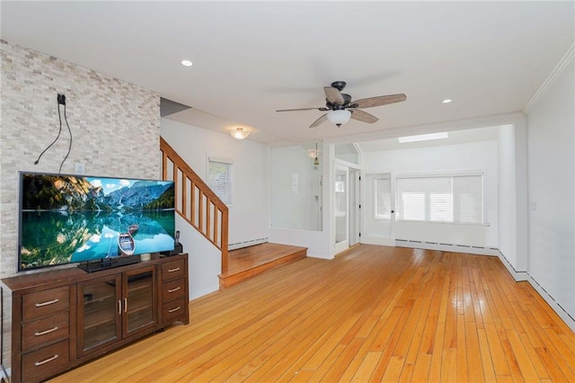 unfurnished living room with a baseboard heating unit, a ceiling fan, light wood-style floors, and stairs