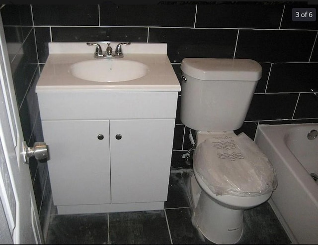 bathroom with vanity, a bath, tile patterned floors, toilet, and tile walls