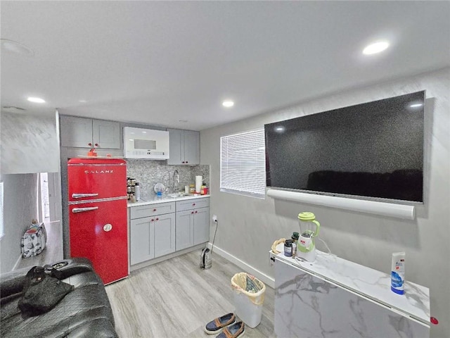 kitchen featuring light wood-style flooring, a sink, decorative backsplash, light countertops, and recessed lighting
