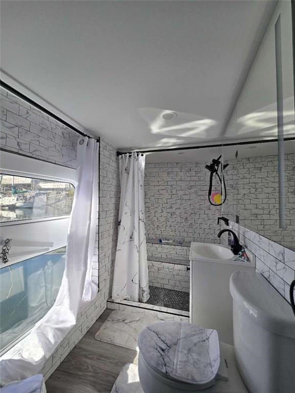 bathroom with vanity, brick wall, toilet, and a shower with shower curtain