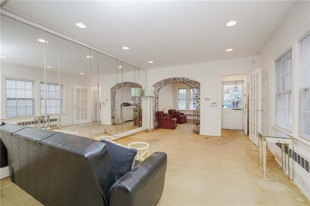 living room with light colored carpet, arched walkways, radiator heating unit, recessed lighting, and baseboards