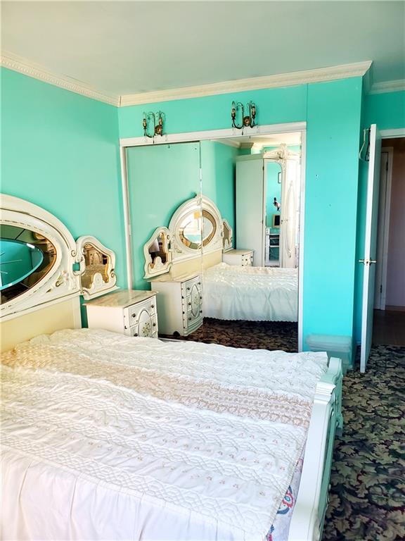 carpeted bedroom with a closet and crown molding