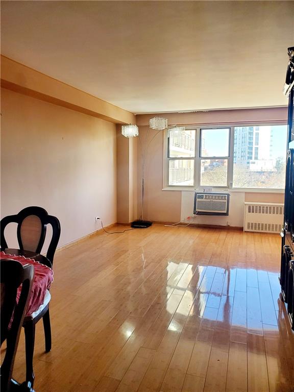 interior space featuring hardwood / wood-style flooring, a wall mounted air conditioner, and radiator