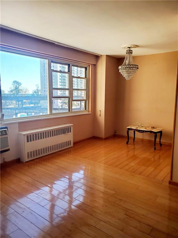 spare room with light wood finished floors, radiator heating unit, a chandelier, and a wall mounted AC