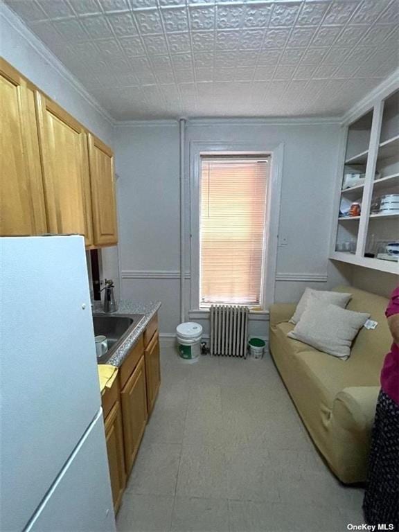 kitchen with radiator, crown molding, sink, and white fridge