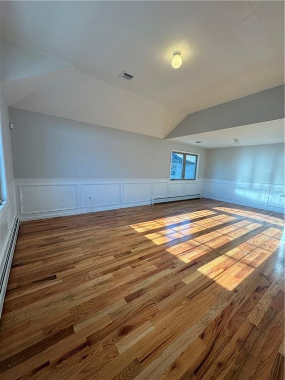 additional living space with a baseboard radiator, vaulted ceiling, and hardwood / wood-style flooring