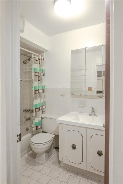 full bathroom featuring vanity, shower / bathtub combination with curtain, wainscoting, tile walls, and toilet