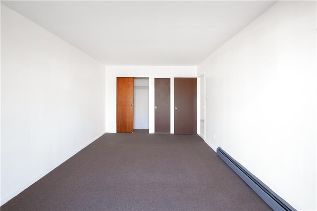 unfurnished bedroom with dark colored carpet, a baseboard radiator, and a closet