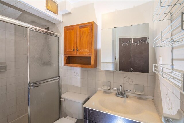 bathroom with vanity, toilet, a shower with door, and decorative backsplash