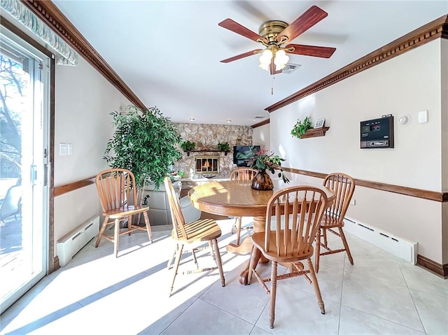 dining room featuring a baseboard heating unit, a fireplace, crown molding, and visible vents