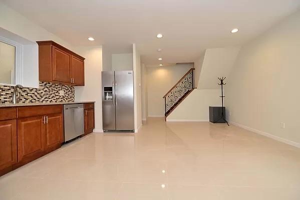 kitchen with appliances with stainless steel finishes, sink, light tile patterned floors, and backsplash