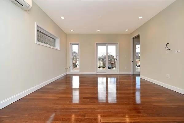 empty room featuring dark wood-type flooring and a wall unit AC