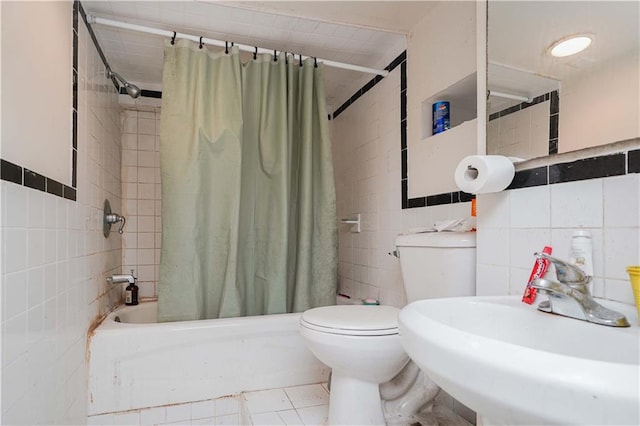 bathroom with tile patterned flooring, toilet, a sink, tile walls, and shower / bath combo