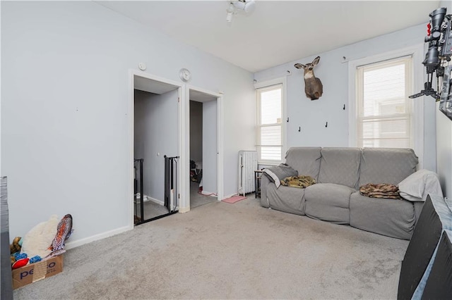 carpeted living room with radiator heating unit and baseboards