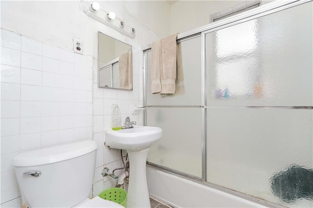 full bath with toilet, enclosed tub / shower combo, and tile walls