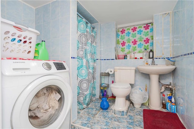 washroom with laundry area, a sink, washer / dryer, and tile walls