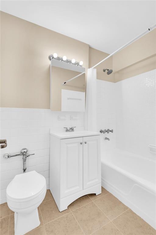 full bathroom featuring tile patterned flooring, vanity, tile walls, and toilet