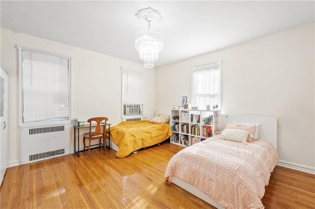 bedroom featuring radiator heating unit, a chandelier, and wood-type flooring