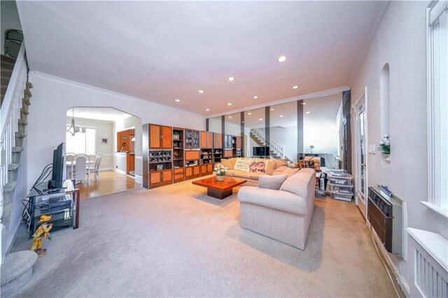 living room featuring light colored carpet, heating unit, crown molding, and an inviting chandelier