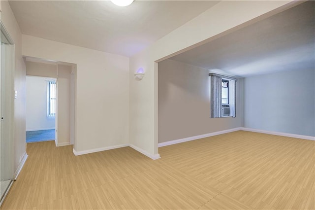 empty room with light wood-type flooring, cooling unit, and baseboards