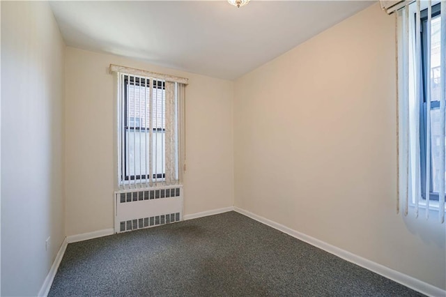 unfurnished room with radiator heating unit, baseboards, and dark carpet