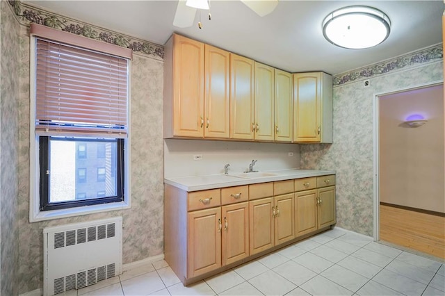 kitchen with light brown cabinets, radiator, wallpapered walls, and light countertops