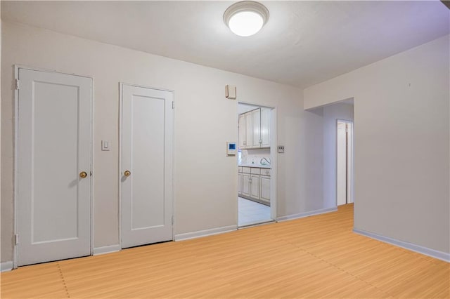 unfurnished room with baseboards and light wood-style flooring