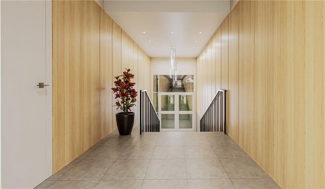 corridor featuring wooden walls and light tile patterned flooring