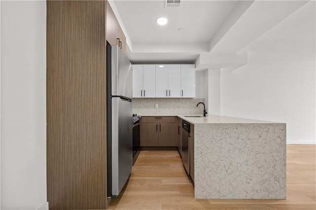 kitchen featuring backsplash, stainless steel appliances, sink, light hardwood / wood-style flooring, and white cabinetry