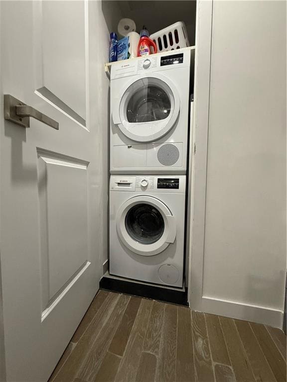 laundry room featuring stacked washing maching and dryer and dark wood-type flooring