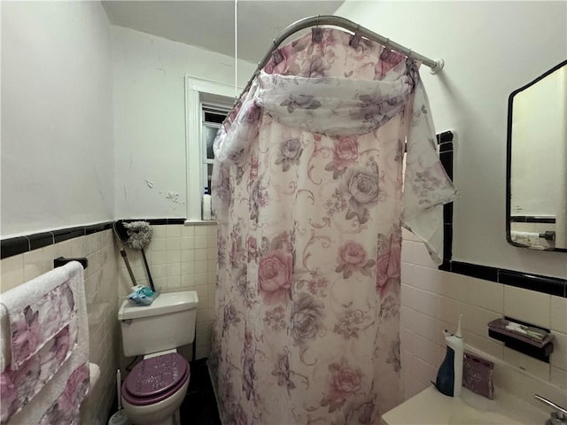 bathroom featuring a shower with curtain, toilet, and tile walls