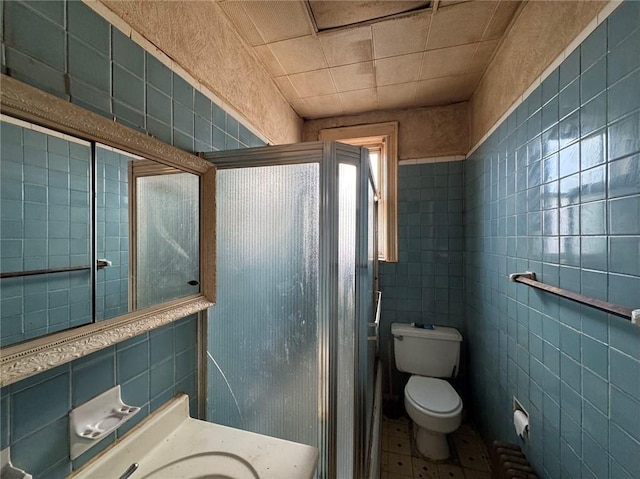 bathroom featuring toilet, tile walls, vanity, and a shower with shower door