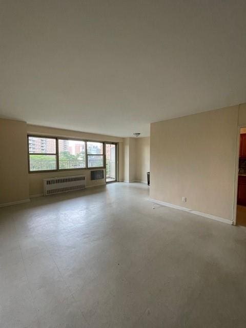 unfurnished room with radiator, baseboards, and plenty of natural light