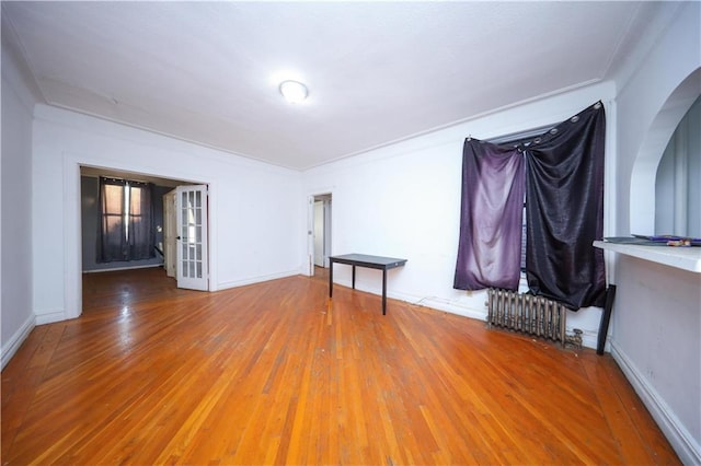 unfurnished room featuring radiator heating unit, hardwood / wood-style flooring, and french doors