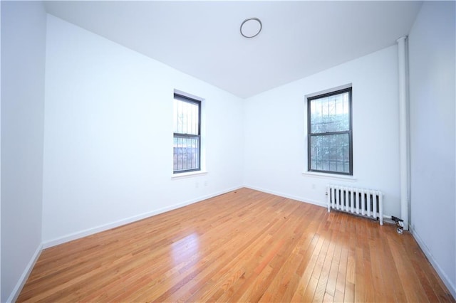 empty room with light hardwood / wood-style flooring and radiator heating unit