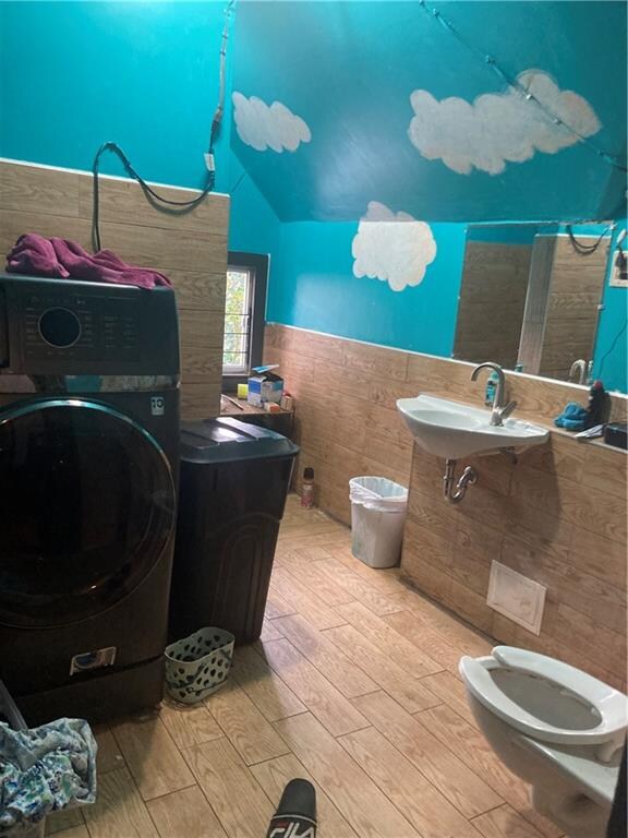 bathroom featuring washer / dryer, vaulted ceiling, hardwood / wood-style floors, and sink