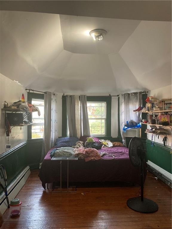 bedroom with lofted ceiling, baseboard heating, and dark hardwood / wood-style floors