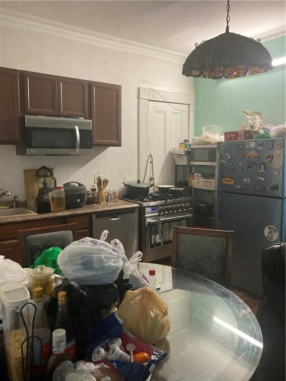 kitchen featuring stainless steel appliances, crown molding, dark brown cabinetry, and sink