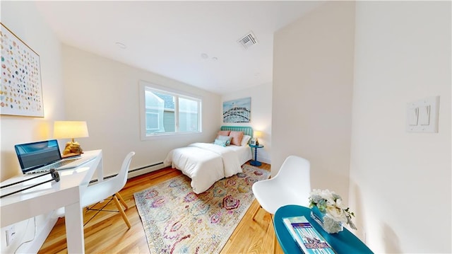 bedroom with wood-type flooring and a baseboard heating unit