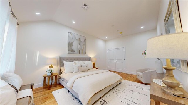 bedroom with light wood-type flooring, a closet, and lofted ceiling