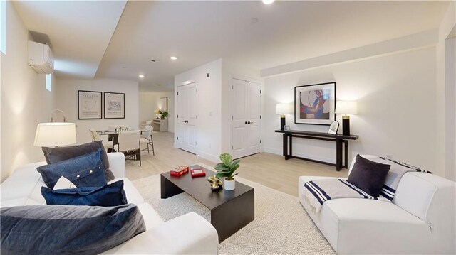 living room featuring a wall mounted AC and light hardwood / wood-style floors