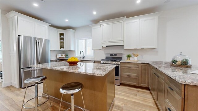 kitchen with white cabinetry, light stone counters, and appliances with stainless steel finishes