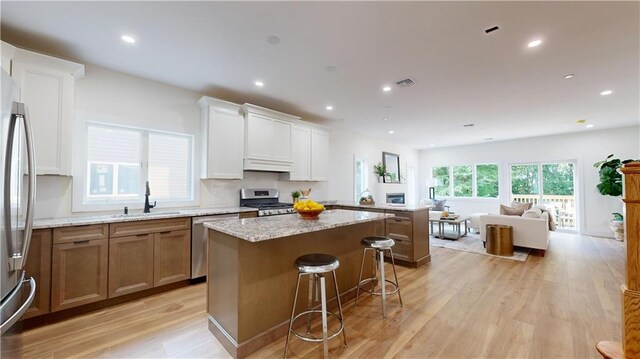 kitchen with white cabinets, appliances with stainless steel finishes, a kitchen island, and sink