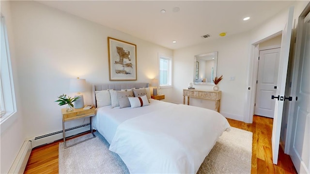 bedroom featuring light wood-type flooring and a baseboard radiator