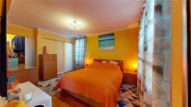 bedroom with light hardwood / wood-style floors, a closet, and ornamental molding