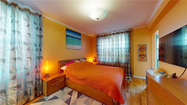 bedroom with ornamental molding and light hardwood / wood-style flooring